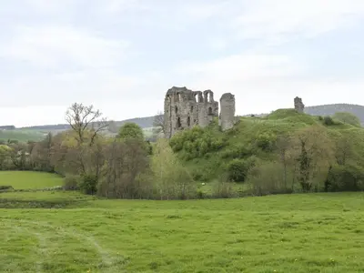 a castle on a hill in a field at Castle Cottage in Clun