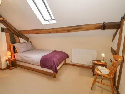 a bedroom with a bed and a chair and a skylight at The Gallery in Craven Arms