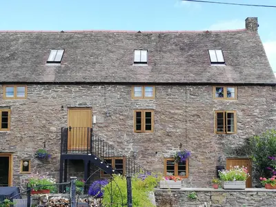 an old stone house with a staircase in front of it at The Gallery in Craven Arms