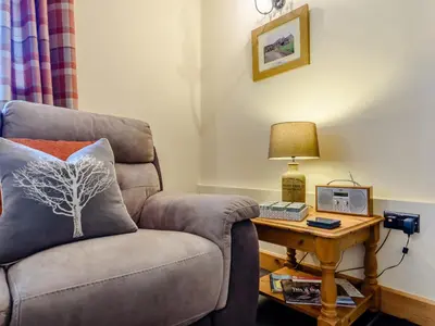 a living room with a chair and a table with a lamp at The Stables in Llanfair Caereinion