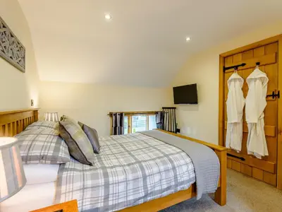 a bedroom with a bed and two dresses hanging on a wall at The Stables in Llanfair Caereinion