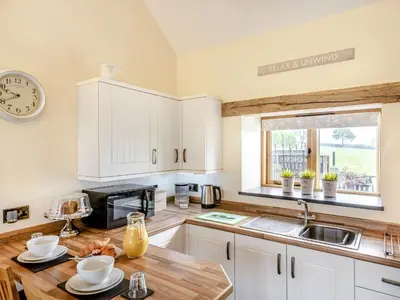 a kitchen with white cabinets and a sink and a microwave at The Granary in Llanfair Caereinion
