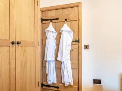 a closet with white shirts hanging on a door at The Granary in Llanfair Caereinion