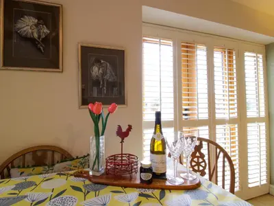 a dining room table with a bottle of wine and flowers at The Milking Parlour in Leominster