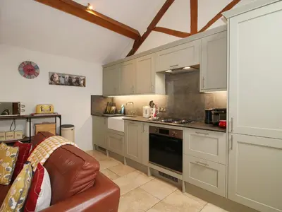 a kitchen with white cabinets and a brown leather couch at The Milking Parlour in Leominster