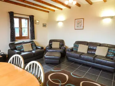 a living room with a leather couch and a table at Y Bwthyn in Ystrad Meurig