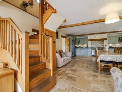 a living room with a staircase and a kitchen at The Hayloft in Knighton