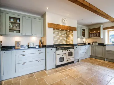 a large kitchen with white cabinets and appliances at The Hayloft in Knighton
