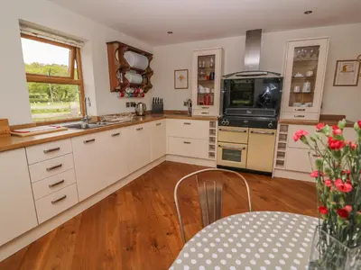 a kitchen with white cabinets and a table at The Farmhouse in Capel Bangor