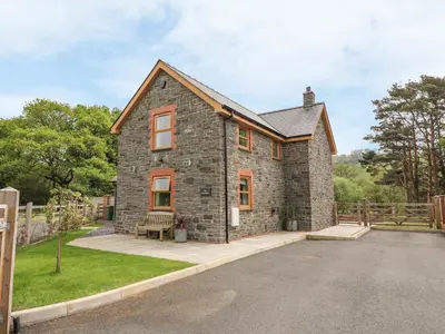 a stone house with a bench in front of it at The Farmhouse in Capel Bangor