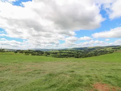 a field with green grass and a cloudy sky at Valley View in Rhayader