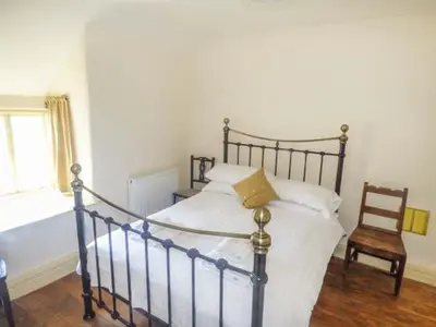 a bedroom with a bed and a chair and a window at Tyn Llwyn in Dolgellau