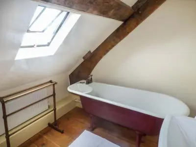 a attic bathroom with a bath tub and a window at Tyn Llwyn in Dolgellau