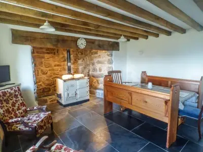 a living room with a wooden table and a fireplace at Tyn Llwyn in Dolgellau