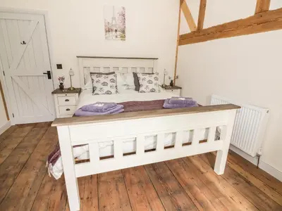 a bedroom with a white bed with a wooden floor at Tynddol Barn in Llanbadarn-fynydd