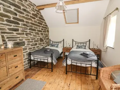 two beds in a room with a stone wall at Tynddol Barn in Llanbadarn-fynydd
