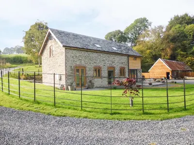 a stone house with a fence in front of it at Tynddol Barn in Llanbadarn-fynydd