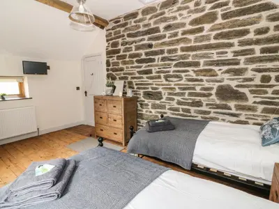 a bedroom with a stone wall with a bed and a stone at Tynddol Barn in Llanbadarn-fynydd