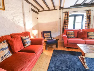 a living room with red couches and a blue rug at The Corn Store in Corwen
