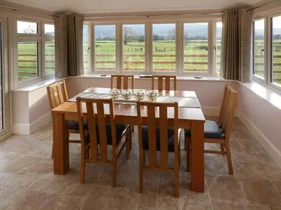 a dining room with a table and chairs and windows at Rose Cottage in Winforton