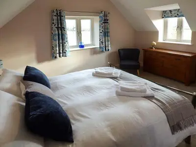 a bedroom with a large bed with two pillows on it at Rose Cottage in Winforton