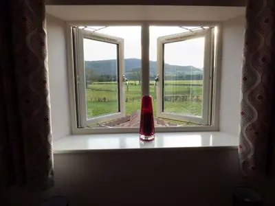 a window with a red vase sitting on a window sill at Rose Cottage in Winforton