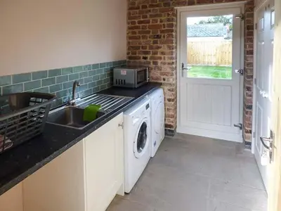 a kitchen with a sink and a washing machine at Rose Cottage in Winforton