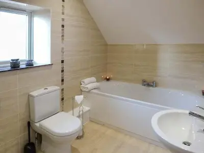 a bathroom with a white tub and a toilet and a sink at Rose Cottage in Winforton