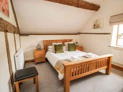 a bedroom with a wooden bed and a chair at The Old Farmhouse in Craven Arms