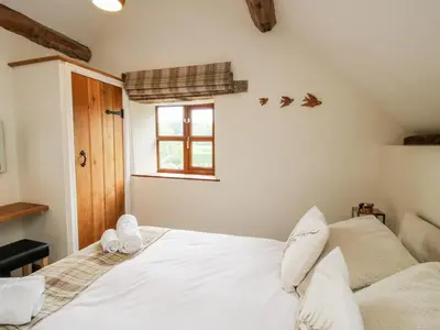 a bedroom with a white bed and a window at The Old Farmhouse in Craven Arms