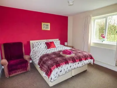 a red bedroom with a bed and a chair at The Willows in Ellesmere