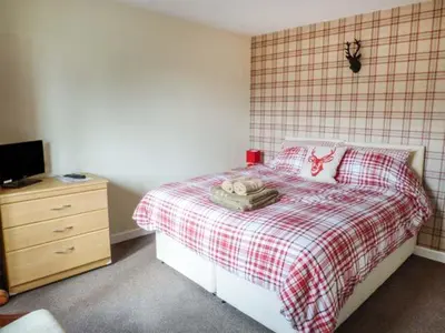 a bedroom with a bed with a red and white plaid blanket at The Willows in Ellesmere