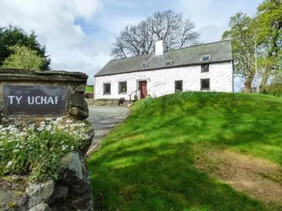 a white house with a sign in front of it at Ty Uchaf in Llangwm