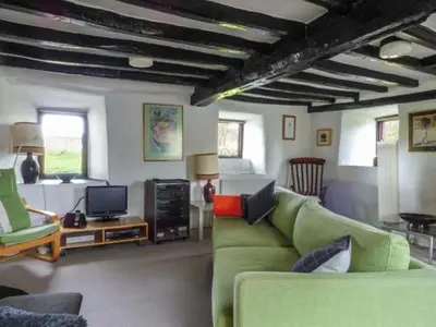 a living room with a green couch and a tv at Ty Uchaf in Llangwm
