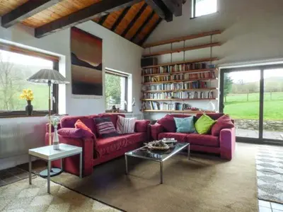 a living room with two red couches and a book shelf at Ty Uchaf in Llangwm
