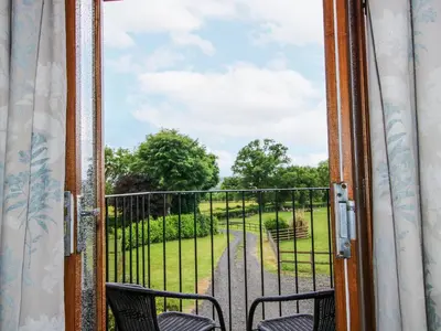 an open door to a balcony with a view of a park at The Hay Loft in Craven Arms