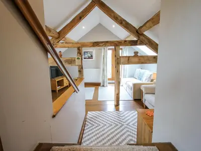 an open living room with wooden ceilings and a stairway at The Hay Loft in Craven Arms