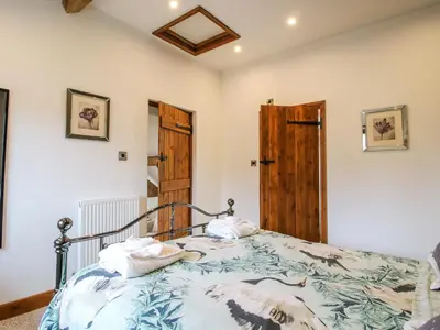 a bedroom with a bed and a wooden door at The Hay Loft in Craven Arms