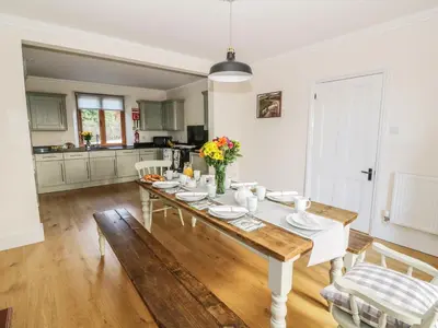 a kitchen with a wooden table with flowers on it at Oakwood House in Saint Harmon