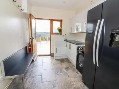 a kitchen with a black refrigerator and a tile floor at Oakwood House in Saint Harmon