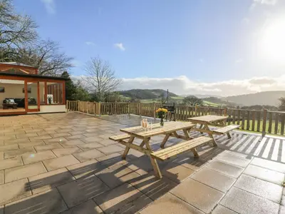 a patio with two picnic tables on a stone patio at Oakwood House in Saint Harmon