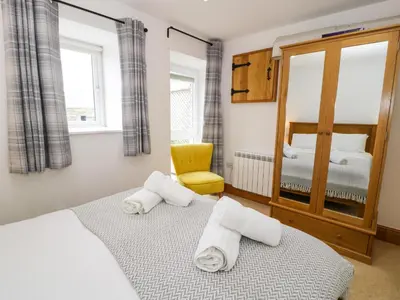 a bedroom with two beds and a yellow chair at Bwthyn Bach in Llanddwywe