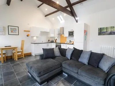 a living room with a couch and a kitchen at Bwthyn Bach in Llanddwywe
