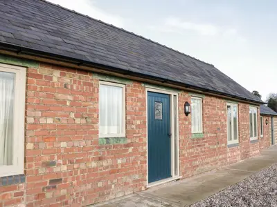 a brick building with a blue door and windows at Swallow Barn in Walford
