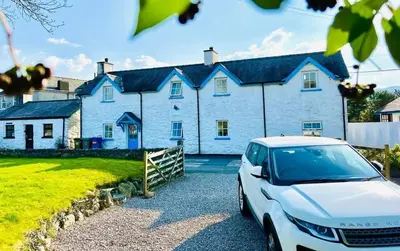 a white house with a car parked in front of it at Pen Y Bont Cottage Llanuwchllyn Bala in Llanuwchllyn