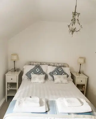 a bedroom with a bed with pillows and a chandelier at Pen Y Bont Cottage Llanuwchllyn Bala in Llanuwchllyn