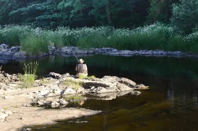 a man sitting on the bank of a river fishing at The Owls in Builth Wells