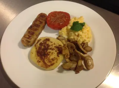 a plate of breakfast food with eggs sausage and mushrooms at The Owls in Builth Wells