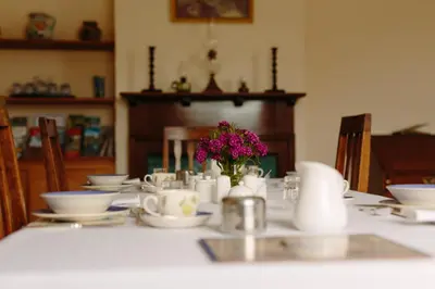 a table with white dishes and a vase of flowers at Hordley Hall in Ellesmere