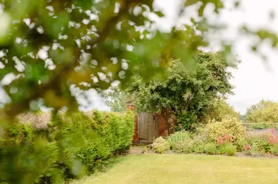 a garden with a wooden gate and some bushes at Hordley Hall in Ellesmere